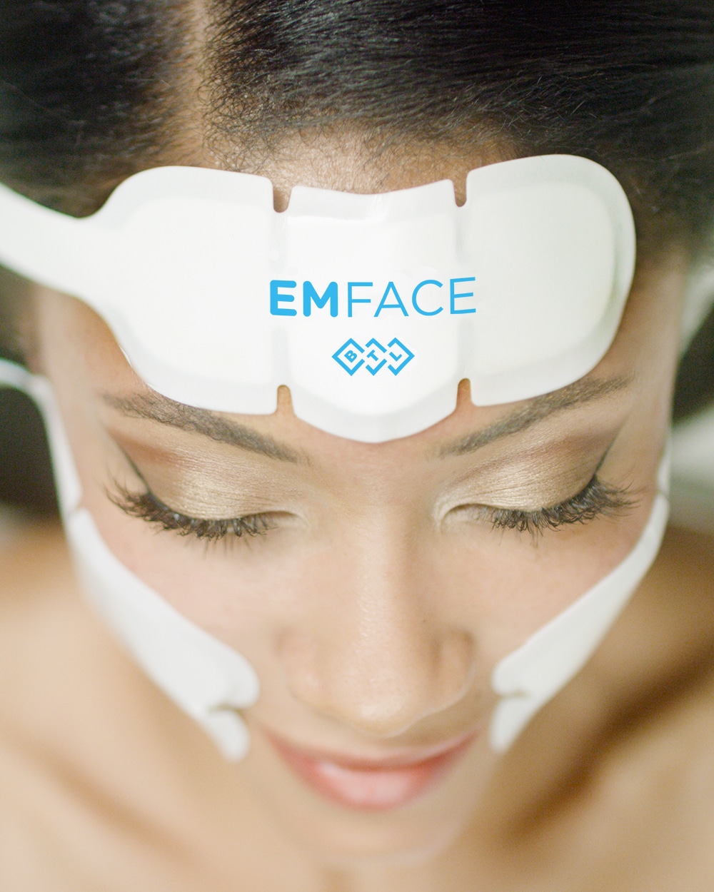 Woman wears the EMface applicators to firm and tighten skin.