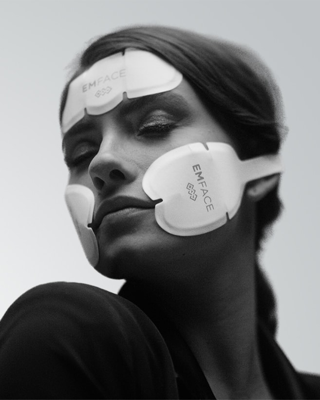 Black and white image of a woman wearing the EMface applicators to achieve non-invasive facelift.