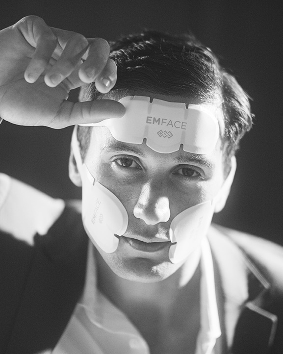 Black and white image of a man wearing the EMface applicator pads.